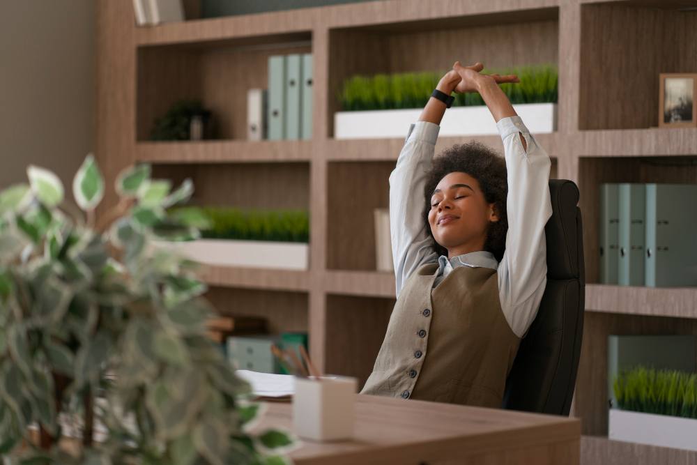 Une femme dans un bureau avec des plantes, elle s'étire et sourit